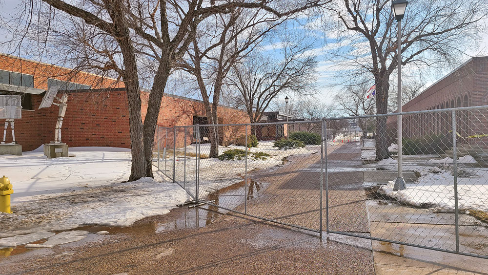 Library doors still open though north side sidewalk is fenced off